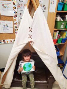 enfant sous un tipi tient un dessin dans ses mains